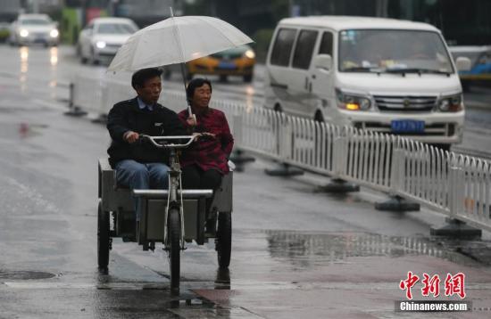 資料圖：民眾在雨中出行。<a target=